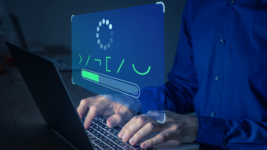 A man types on a laptop while a coded message is displayed on the screen.